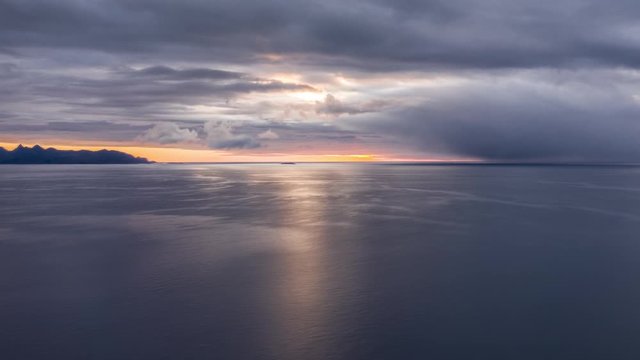 Dramatic sea sunset on the Andoya island. Thick stormy clouds cover the sky, narrow strip of orange sky between the sky and dark sea waters.