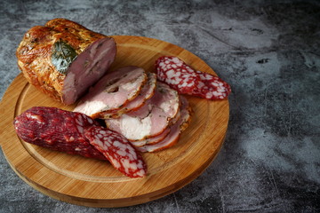 Smoked meat and salami on a cutting Board on a dark background