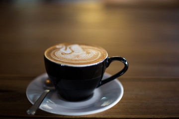 Cup of hot cappuccino on the wooden table background.