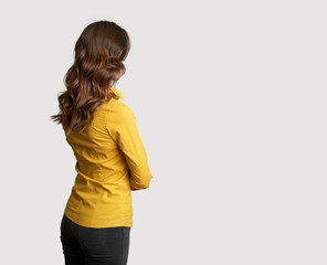 Back view of a business woman in yellow shirt is looking away