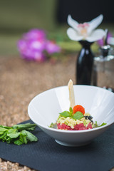 Classic traditional tartar salad laid in a round shape, stylish serving in an oriental style table in a restaurant.