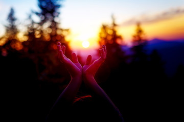 sun in hands. Sunset on the background of raised hands.