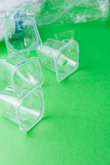 Top view of plastic containers on green background, for recycling, in vertical with copy space