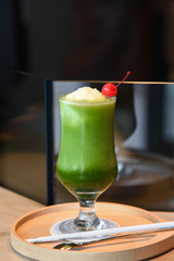 Glass of fresh and healthy green smoothie on wooden teble.