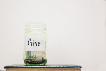  Coins in glass jar with Give word written text label for giving and donation concept