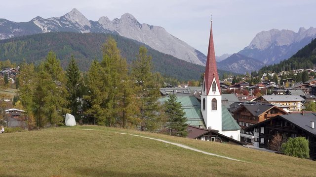 Close up view of the church spire and roof tops of Seefeld in Tirol in Autumn with the mountains of the alps in the background. Austria