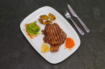 Grilled beef or veal meat steak with lemon, carrots, lettuce and potatoes. Juicy and very tasty dish of Italian cuisine