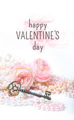 happy Valentine's day greeting card. gentle romantic image. pearls, roses and vintage key on white background. close up, soft selective focus