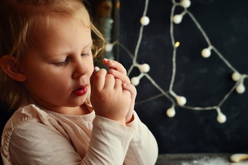 Portrait of a beautiful girl 2-3 years old. The girl folded her arms. The child looks in his palm. New Year and Christmas miracle.