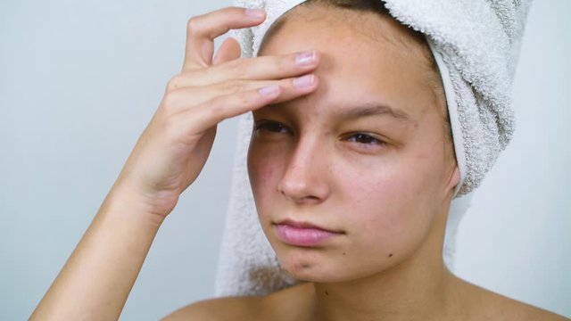 Teenage girl examining her face with acne after bath