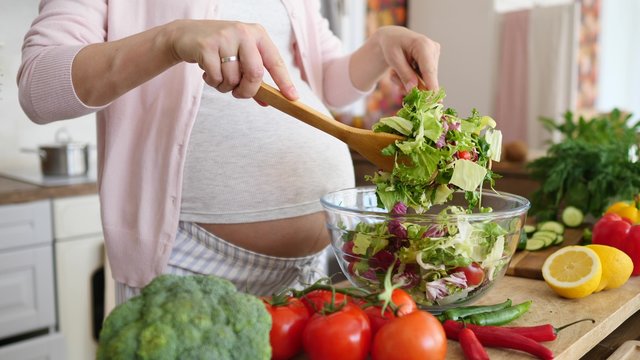 Pregnancy Diet Nutrition Concept. Pregnant Woman Preparing Meal On Kitchen, Making Salad.