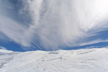 Deep snow powder, blue sky with white fluffy clouds at high altitude on a sunny winter day. Mountain range of Uludag, Turkey.