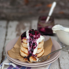 Homemade cheesecakes with sour cream and blueberry jam on a ceramic plate. Served with a napkin 