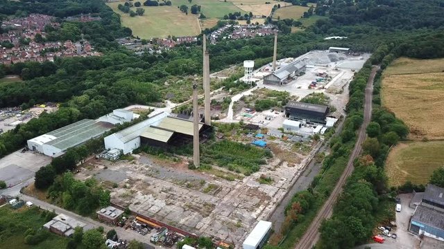 Aerial shot over an abandoned industrial area with large stone chimneys.