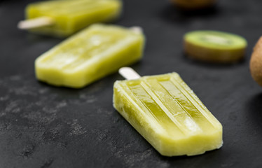 Fresh made Kiwi Popsicles on a slate slab (close-up shot; selective focus)