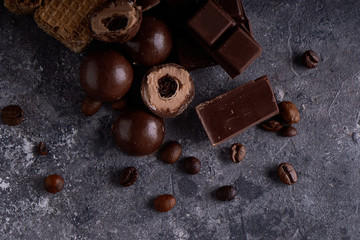 broken black and white chocolate. Pieces of chocolates on a gray stone table