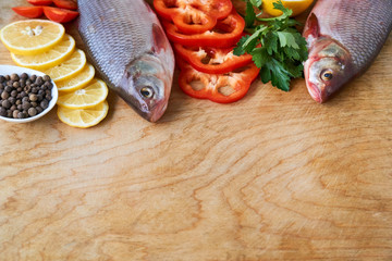 Raw roach fish with lemon and pepper on a wooden background