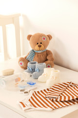 baby clothes with hygiene items and teddy bear doll