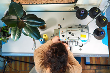 Seamstress works with sewing machine. Workplace of tailor. Top view.
