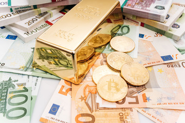 Bitcoin BTC Gold coins with bills of euro banknotes and gold bullion. Bitcoin and gold lie on Euro banknotes