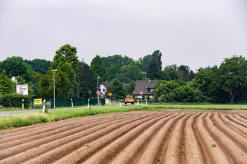 Plowed field near the village. Field on the background of the village.