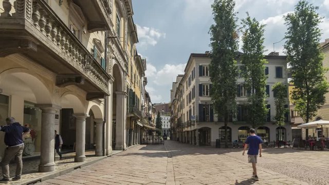 Some people walking in a street in the historic center of the city of Varese, city garden, on a spring afternoon.