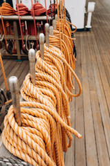 Old sailboat, closeup of wooden cleats with nautical moored ropes.