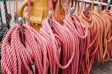 Old sailboat, closeup of wooden cleats with nautical moored ropes.