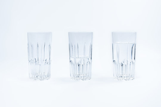 Three glasses filled with water differently on white background. A full, half full and epty glasses in isolated studio background