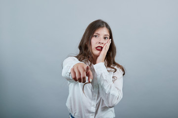 Charming young woman in fashion white shirt isolated on gray background in studio keeping hand on...