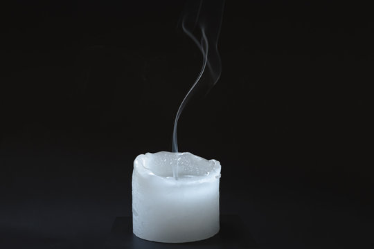 Smoke rising from a dipped candle. Blue smoke of a candle in dark background, concept of air pollution from oil products burning