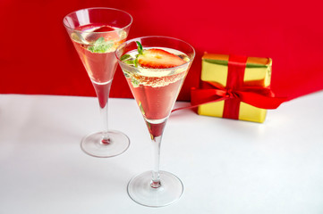 Two champagne glasses with strawberries and a gift in the background Valentine's Day concept