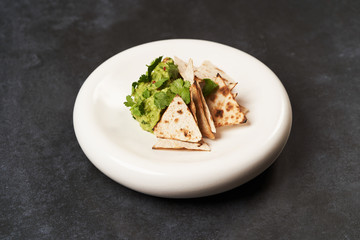 Guacamole with pita chips on white plate. Chef's signature dish