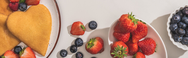 top view of tasty heart shaped pancakes with berries and mint on white background, panoramic shot