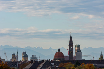 Rooftop view of churches in Munich with alpine mountains in the background