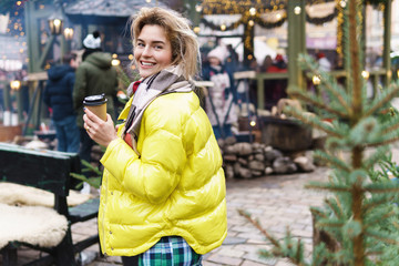 Happy woman with a cup of hot drink on the Christmas market