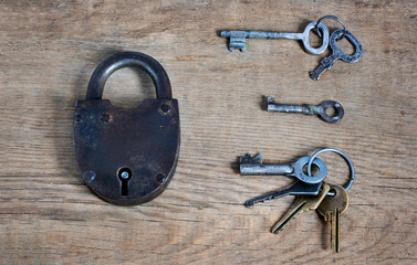 old fashioned rusty lock with keys on wooden surface