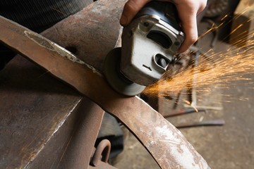 Blacksmith Using Angle Grinder On Edge Of Metal Tool