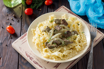 Italian Cuisine. Pasta with meat liver and onion sauce on wooden table.