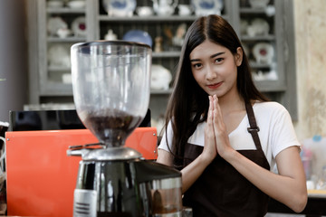 Beautiful girl barista give pay to customer or welcome, respect, hello to someone. It is a Thai culture. She look friendly, Small business owner and work concept.