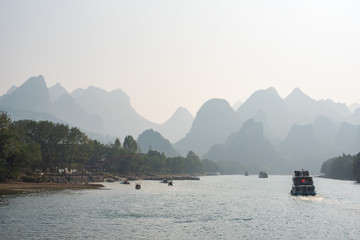 Boat on Li river cruise and karst formation mountain landscape in the fog between Guiling and Yangshuo, Guangxi province, China