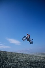 Mountain Biker Jumping Against Blue Sky