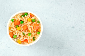 Ramen cup, instant soba noodles in a plastic cup, with green peas and carrot, top shot with a place for text