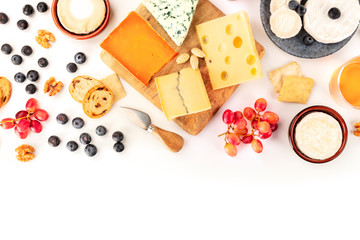 Cheese platter background with a place for text, a flat lay overhead shot on white. Blue cheese, goat cheese, Brie and other sorts with fruits, nuts and almonds, a design template