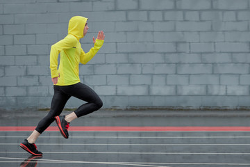 sprinter running from left to right on some outdoor running tracks