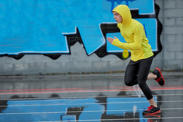 sprinter running from right to left with a blue background, it's yellow