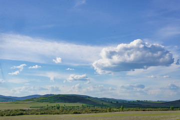 Obraz premium beautiful summer landscape forest and blue sky with clouds. grassy field and mountains. summer rural landscape with the horizon in the afternoon