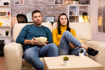 Handsome couple at home eating pop corn and watching TV