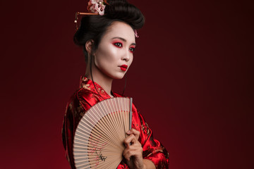 Image of young geisha woman in japanese kimono holding wooden hand fan - obrazy, fototapety, plakaty