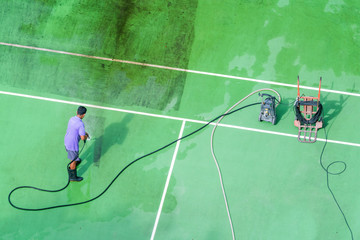 Sink tennis court. Male worker washing a tennis court with water pressure.